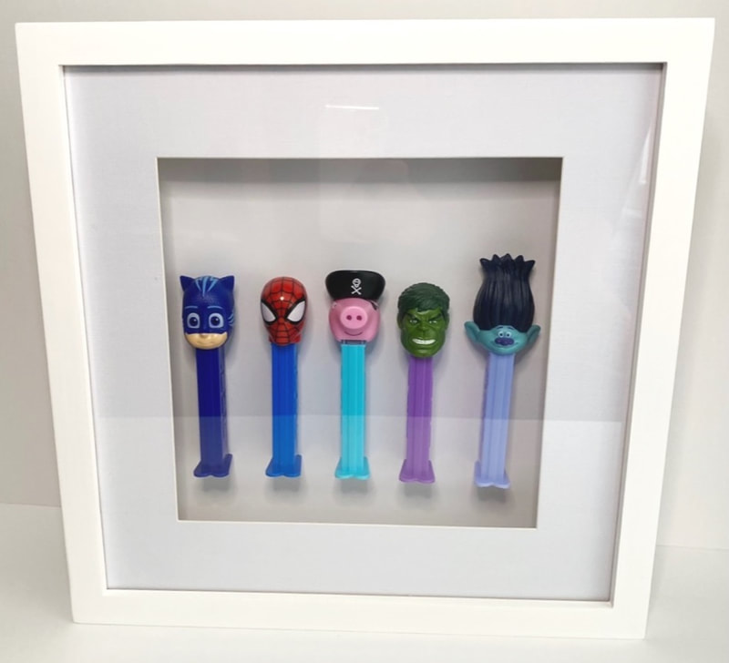 Customised 'Pez' toys in a frame.